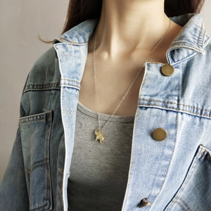Detailed close-up of a golden elephant pendant necklace worn on a casual outfit
