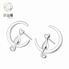 Detailed view of silver asymmetrical earrings with a cute cat sitting on a crescent moon