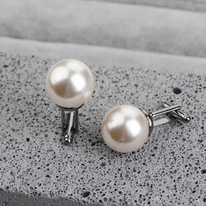 Macro detail of elegant silver cufflinks with large white pearls on grey stone background