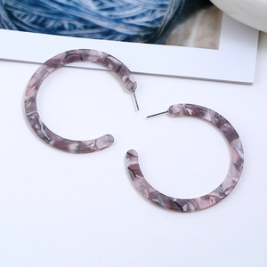 Detail of marble pattern acrylic C-shaped earrings in purple and grey tones