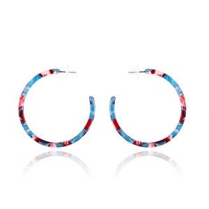 Detail of large C-shaped acrylic earrings with blue, red, and white tortoiseshell pattern