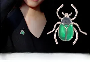 Detail einer Käfer-Brosche mit grüner Emaille an einem schwarzen Blazer am Model