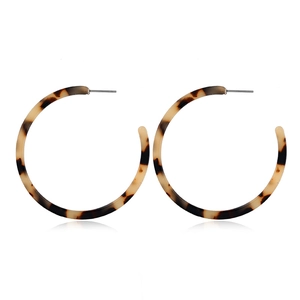 Detailed shot of large tortoiseshell C-shaped acrylic earrings with brown and beige patterns
