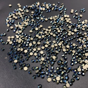 Detailed top view of bulk dark blue round flatback rhinestones on a black background