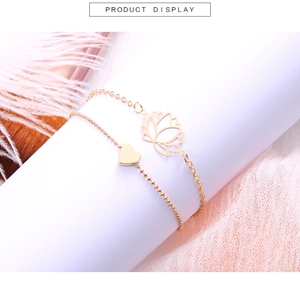Détail d'un ensemble de bracelets dorés avec lotus et cœur sur un fond esthétique délicat