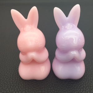 Macro view of pink and lavender rabbit resin molds in a cute prayer pose on black leather