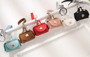 Close-up of six colorful mini PU leather keychains with zippers on white metal grid