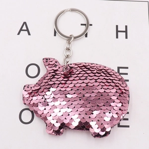 Detail shot of cute pink sequined pig keychain with shiny metallic ring on white background