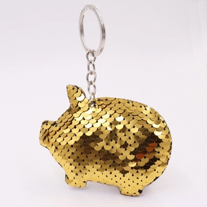 Close-up of cute golden sequined pig keychain with silver metal ring and reflective scales