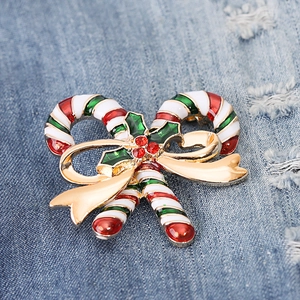 Detailed view of Christmas candy cane brooch with green holly leaves on denim