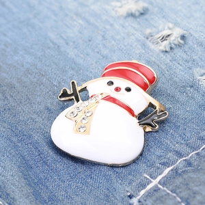 Macro detail of cartoon snowman brooch with red enamel hat and rhinestones on denim