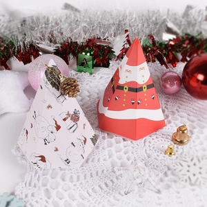 Pyramid Christmas gift boxes with Santa and lamb designs on a white lace tablecloth