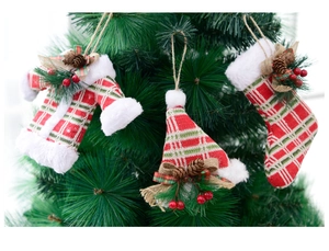 Close-up of knit Christmas sweater, hat, and stocking ornaments on a pine tree branch