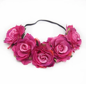 Detail of five rose pink faux silk flowers attached to a black elastic headband floral crown