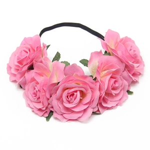 Detail of five pink faux roses and green leaves on an elastic bridal flower headband