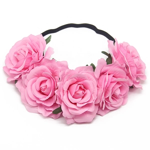 Close-up of five pink faux roses with green leaves on an elastic black headband