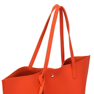 Detailed macro view of orange litchi-textured PU leather tote with silver rivet