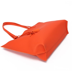 Close-up of orange litchi grain tote bag showing tassel detail and fine leather texture