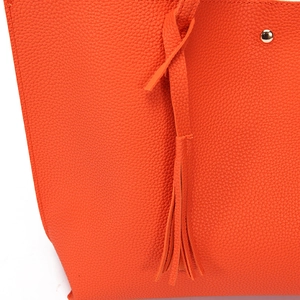 Close-up of bright orange litchi grain PU leather tote bag with tassel and gold stud detail