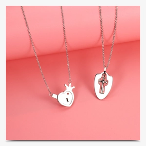 Detail of silver couple necklaces featuring a heart lock with crown and shield key pendant