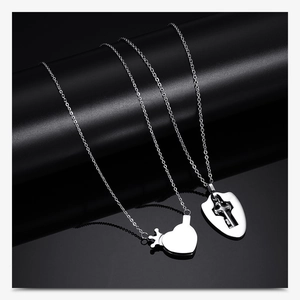 Close-up of silver stainless steel couples necklaces with crown heart and shield pendants
