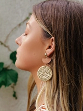 Vue détaillée des boucles d'oreilles bohèmes en bois et rotin sur mannequin