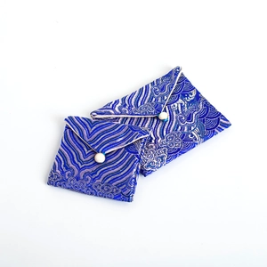 Blue silk brocade jewelry pouches with traditional wave patterns and white button closures