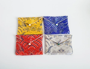 Detailed view of four colorful brocade jewelry pouches with elegant pearl closures