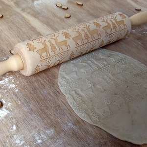 Detail of Christmas reindeer embossed rolling pin creating tree patterns on dough