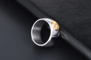 Macro view of wide titanium steel ring with brushed texture and golden bird emblem