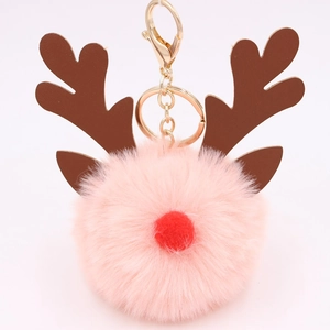 Detail of pink faux fur ball keychain with brown elk antlers and gold metal clasp