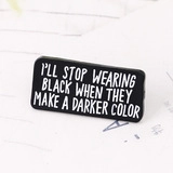 Detail of black enamel pin with white text: I'll stop wearing black when they make a darker color