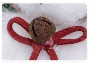 Macro close-up of a vintage rusted bell with a red suede bow and visible glue detail