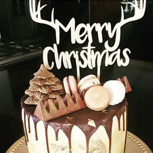 Detailed view of Merry Christmas cake topper with reindeer antlers on a chocolate cake