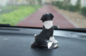 Rear view of a lifelike Border Collie car ornament on a black non-slip dashboard mat