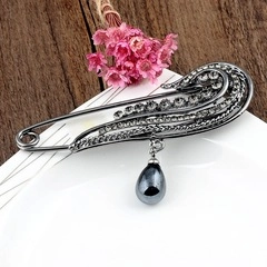 Detailed view of a vintage eagle brooch with white crystals and dark teardrop pendant
