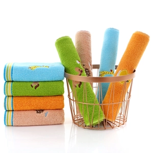 Set of colorful cotton children's towels with animal embroidery in a gold basket