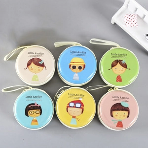 Flat lay of six colorful round tinplate coin purses with cute girl character illustrations