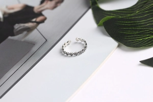 Macro shot of a vintage silver cross ring displayed on a fashion magazine with a green leaf