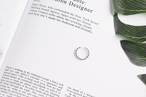 Detail shot of vintage textured silver cross ring on a fashion magazine page background