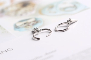 Macro detail of S925 sterling silver hoop earrings with geometric cone pendants