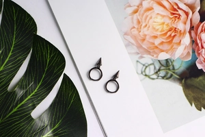 Close-up of black S925 sterling silver hoop earrings with geometric cone charms