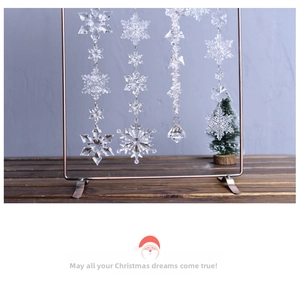 Detailed view of clear acrylic snowflake ornaments hanging on a brown metal display stand