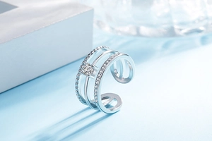 Macro detail of silver triple-layered open ring featuring pavé set crystals on a light blue base
