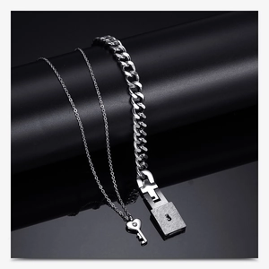 Polished silver heart key necklace and lock bracelet set on reflective dark backdrop
