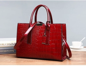 Close-up of elegant red crocodile pattern handbag with metal buckle on a desktop