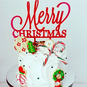 Macro shot of red Merry Christmas acrylic topper on a festive decorated holiday cake