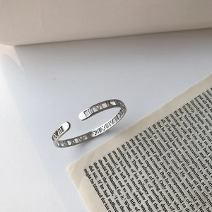 Detailed close-up of S925 silver roman numeral hollow bangle on vintage book pages
