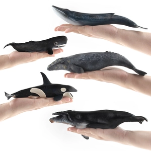 Set of five realistic whale animal models displayed by hand on white background