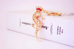 Detailed macro view of a golden seahorse keychain with red rhinestones on book